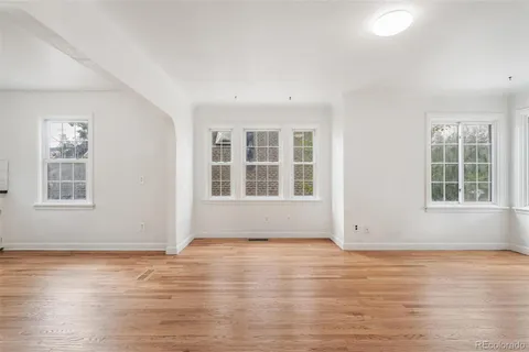 a view of an empty room with wooden floor and windows