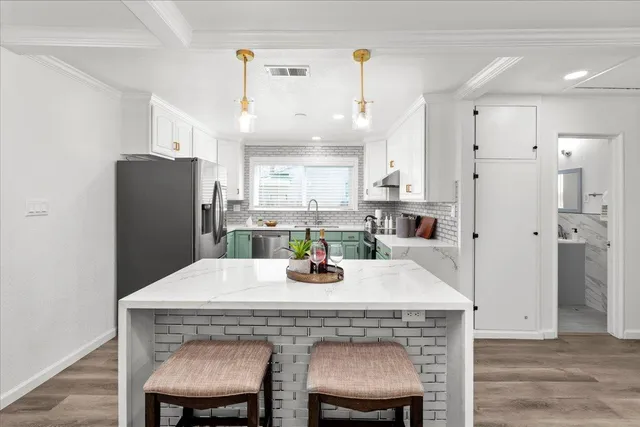 a kitchen with stainless steel appliances a dining table chairs and refrigerator