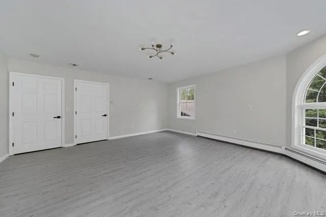 a view of an empty room with a window and wooden floor