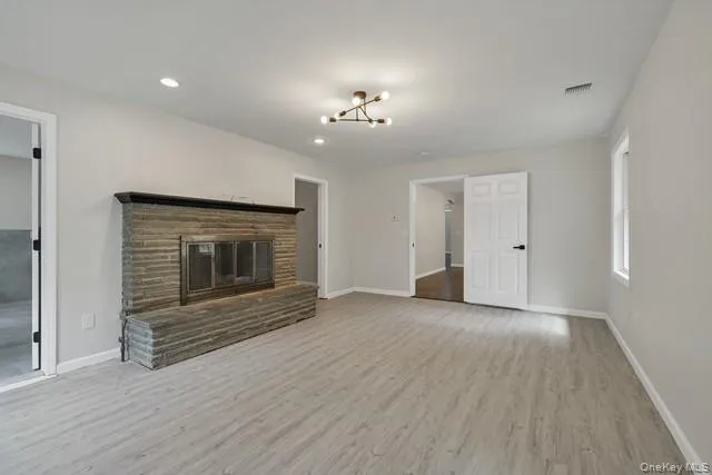 an empty room with wooden floor fireplace and windows