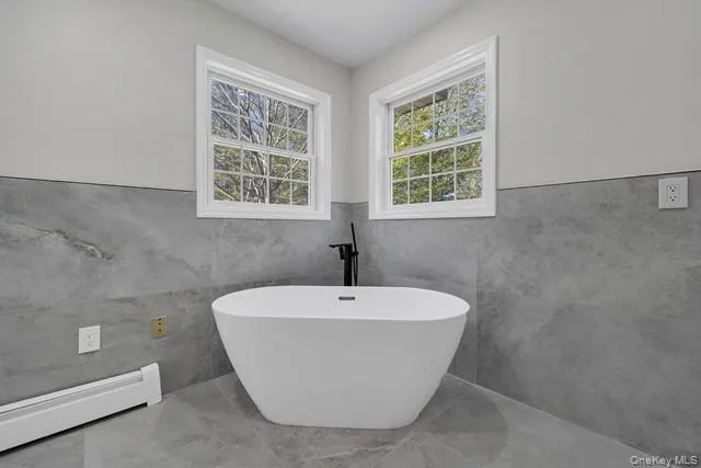 a white bath tub sitting in a bathroom next to a window