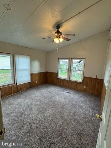 an empty room with windows and fan