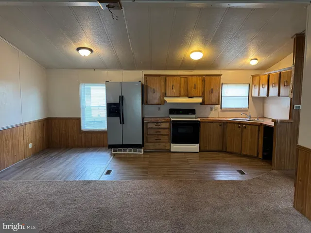 a large kitchen with stainless steel appliances granite countertop a refrigerator and a sink