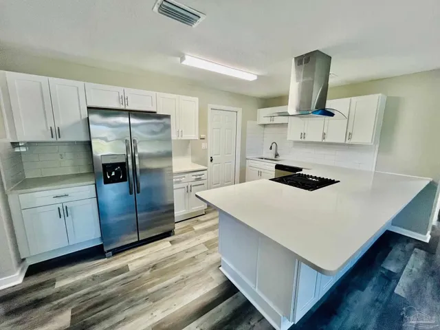 a large white kitchen with wooden floor
