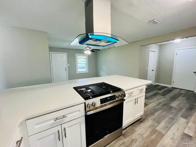 a living room with stainless steel appliances furniture a refrigerator and a wooden floor