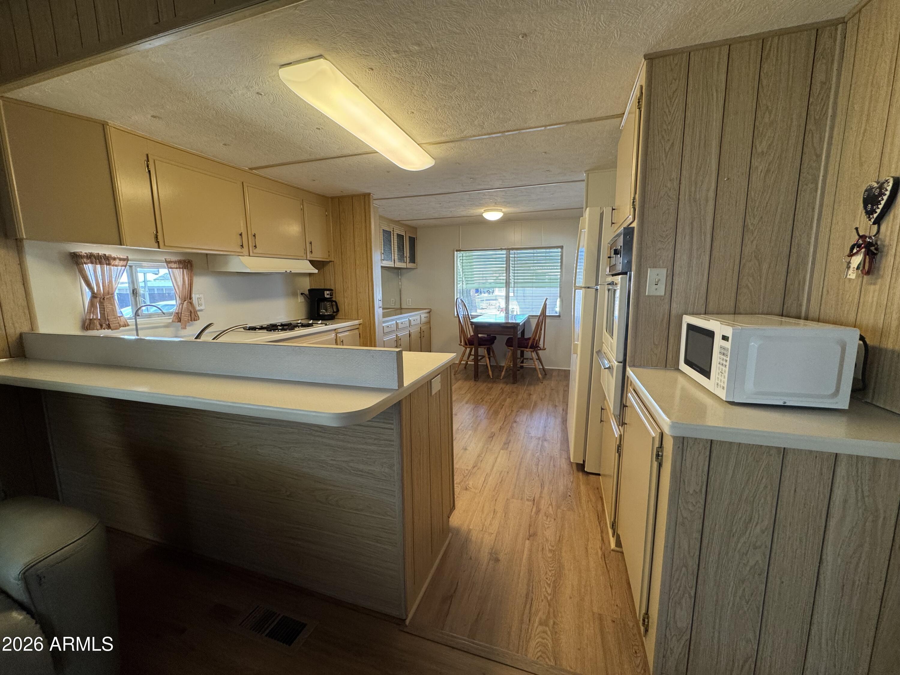 269 North Winchester Road, Unit 36 Apache Junction, AZ 85119 - Photo 4 of 19 a kitchen with stainless steel appliances a sink a stove top oven a wooden floor a dining table and chairs