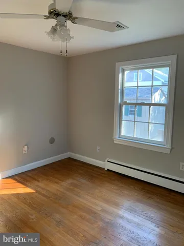 an empty room with wooden floor fan and windows