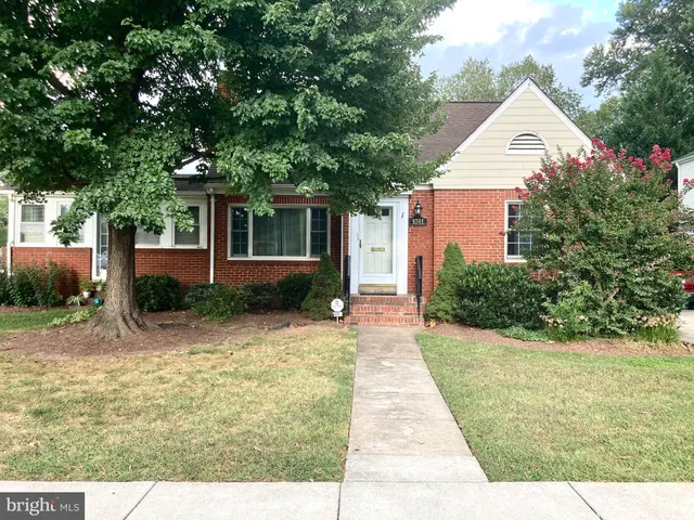 a view of a white house next to a yard with potted plants