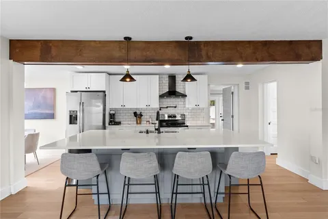 a kitchen with stainless steel appliances a dining table chairs and a refrigerator