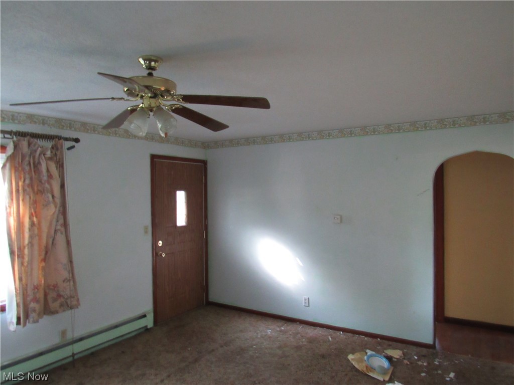 6986 Reed Road Conneaut, OH 44030 - Photo 17 of 22 Empty room featuring a baseboard heating unit, dark carpet, and ceiling fan