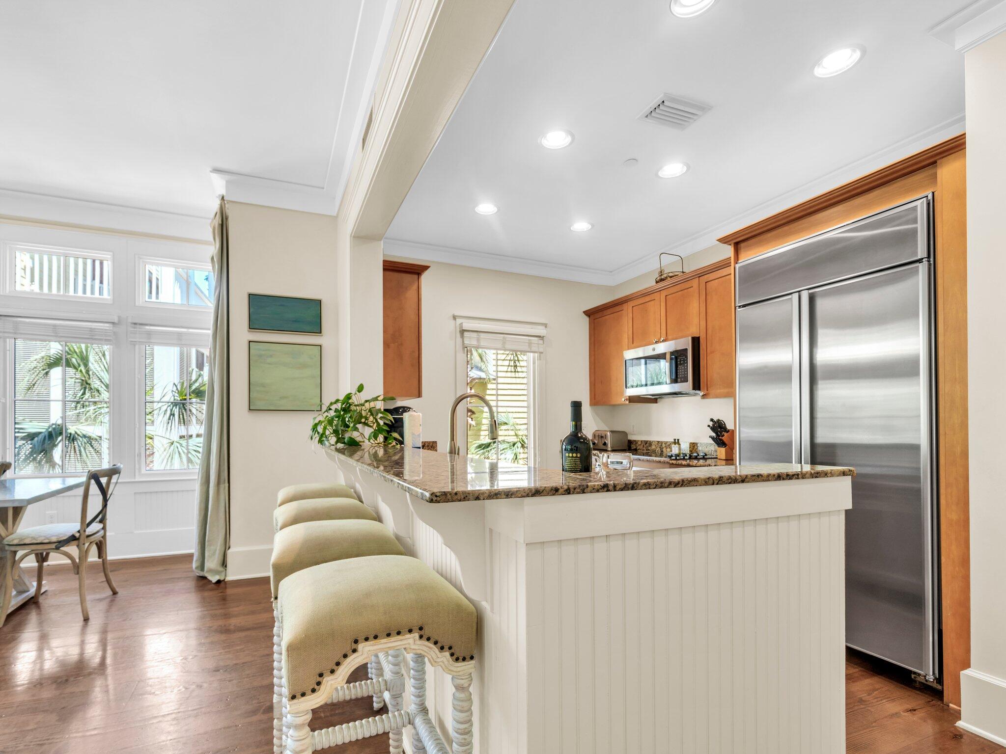 1660 East County Highway 30A, Unit 102 Santa Rosa Beach, FL 32459 - Photo 21 of 48 a living room with stainless steel appliances kitchen island granite countertop a refrigerator a sink dishwasher a dining table and chairs with wooden floor