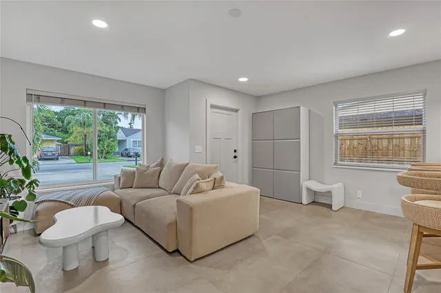 a living room with furniture a flat screen tv and a floor to ceiling window