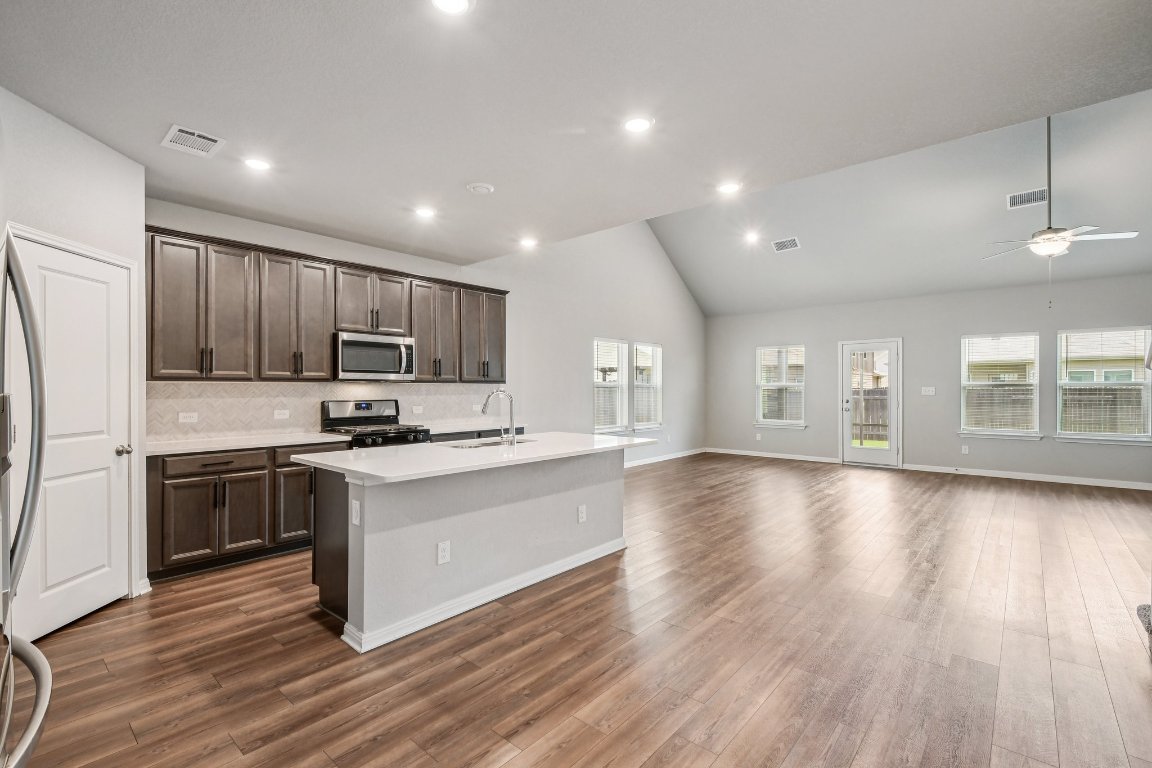 1007 Guadalupe Bass Road Hutto, TX 78634 - Photo 39 of 39 Kitchen featuring decorative backsplash, lofted ceiling, stainless steel appliances, a kitchen island with sink, and open floor plan