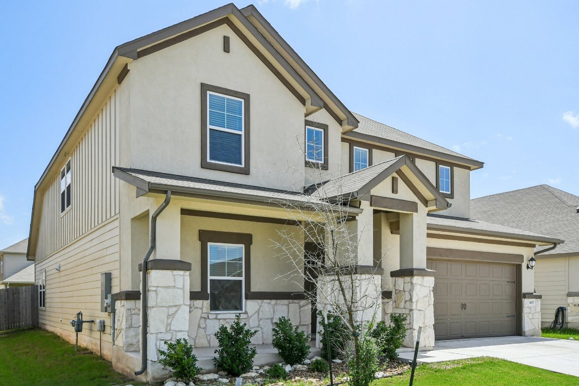 1007 Guadalupe Bass Road Hutto, TX 78634 - Photo 2 of 39 View of front of house featuring stone siding, a garage, stucco siding, driveway, and covered porch