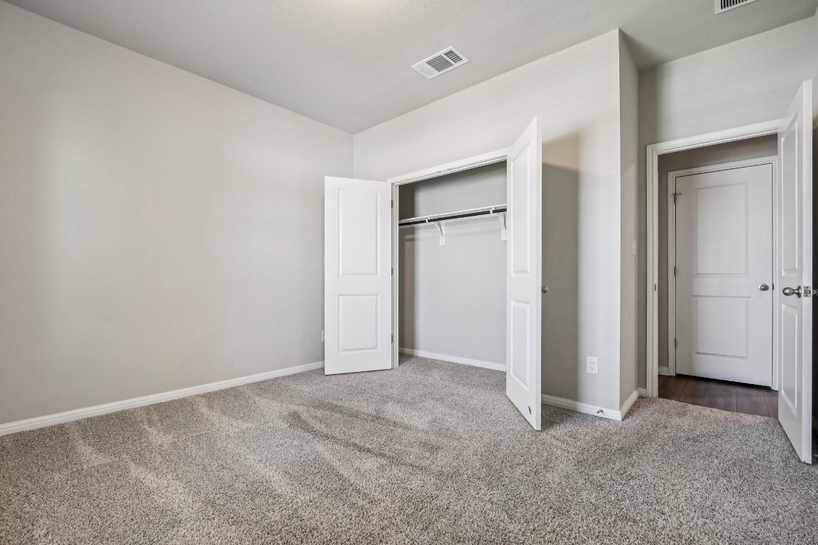 1007 Guadalupe Bass Road Hutto, TX 78634 - Photo 18 of 39 Unfurnished bedroom featuring light carpet and a closet