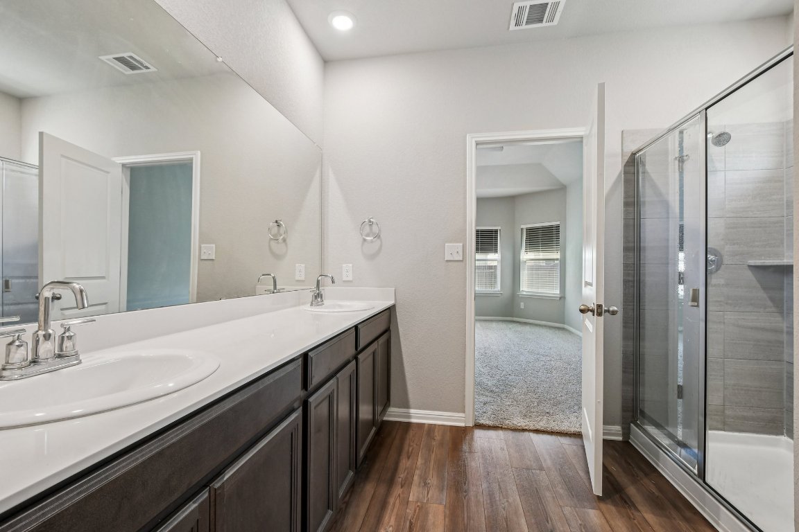 1007 Guadalupe Bass Road Hutto, TX 78634 - Photo 19 of 39 Full bathroom with a stall shower, double vanity, and dark wood-type flooring