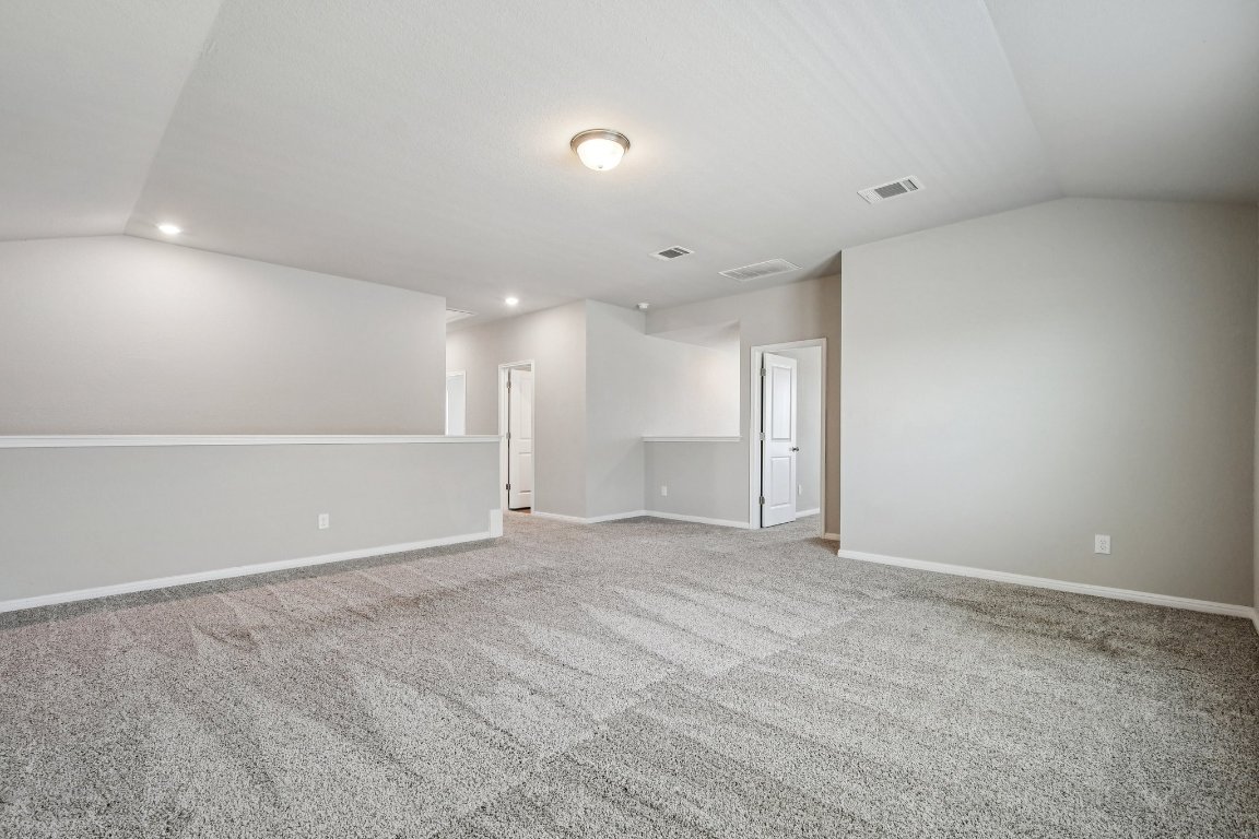 1007 Guadalupe Bass Road Hutto, TX 78634 - Photo 25 of 39 Carpeted spare room featuring vaulted ceiling and recessed lighting