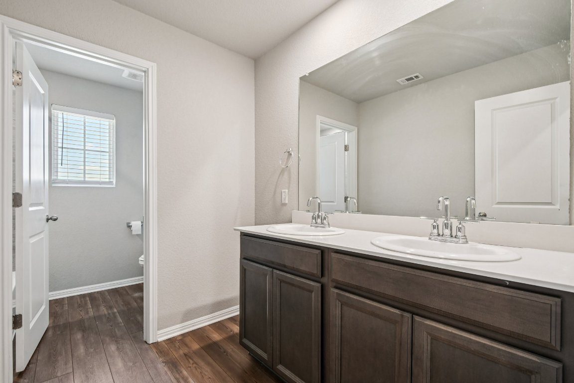 1007 Guadalupe Bass Road Hutto, TX 78634 - Photo 26 of 39 Full bathroom featuring double vanity and dark wood-style flooring
