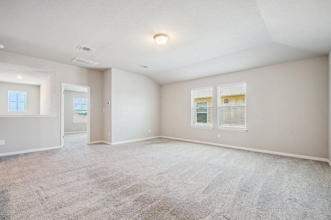 1007 Guadalupe Bass Road Hutto, TX 78634 - Photo 31 of 39 Empty room with light carpet and vaulted ceiling