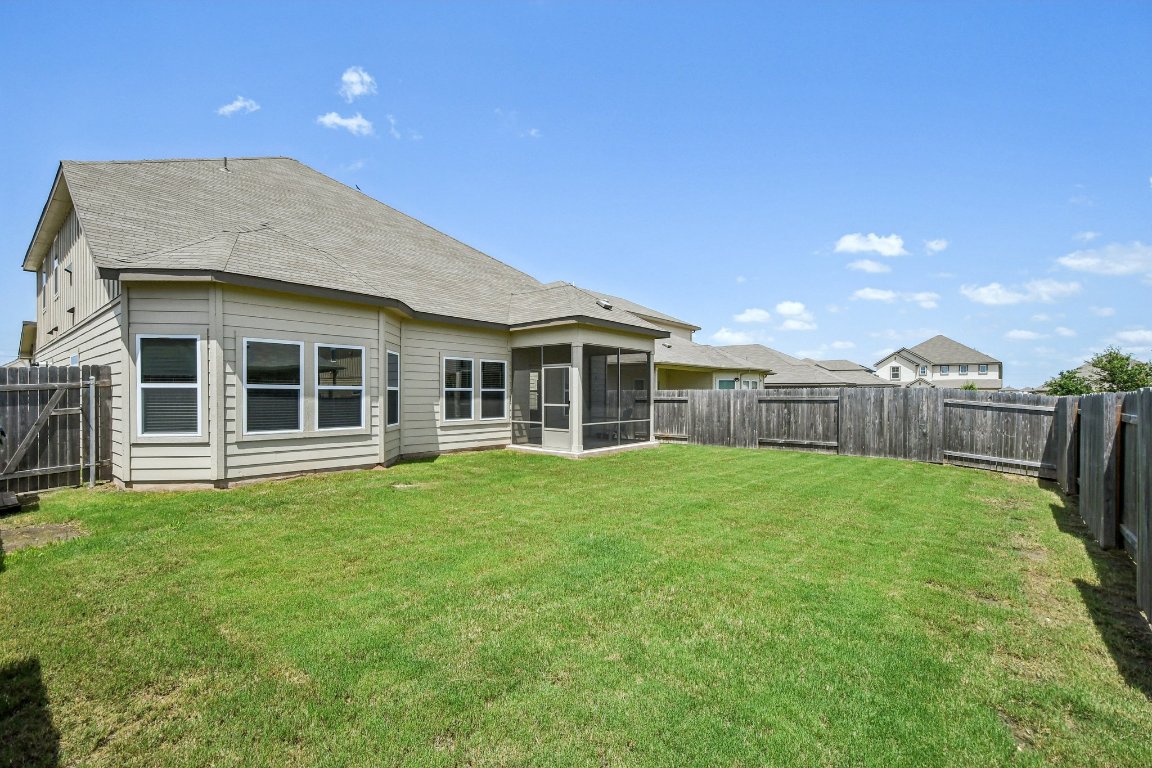 1007 Guadalupe Bass Road Hutto, TX 78634 - Photo 35 of 39 Rear view of house with a shingled roof, a fenced backyard, and a sunroom