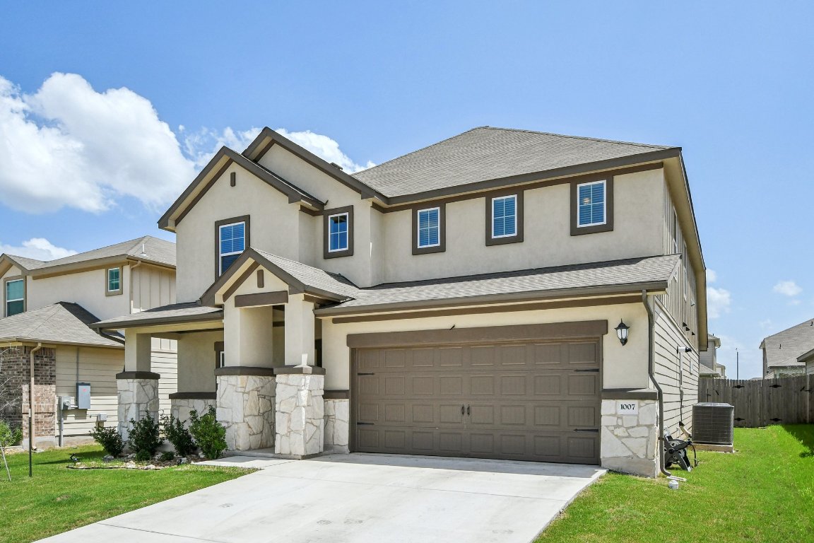 1007 Guadalupe Bass Road Hutto, TX 78634 - Photo 3 of 39 Traditional-style house with stone siding, a garage, driveway, and a shingled roof