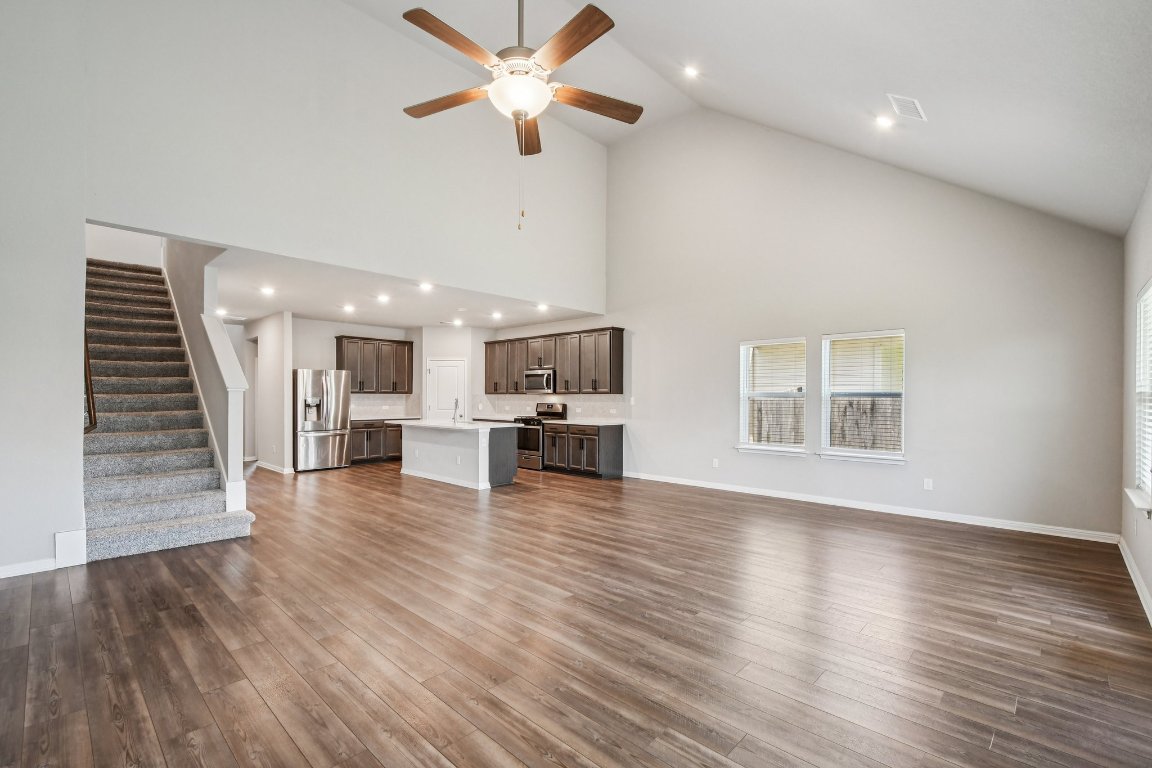 1007 Guadalupe Bass Road Hutto, TX 78634 - Photo 5 of 39 Unfurnished living room featuring stairway, high vaulted ceiling, a ceiling fan, recessed lighting, and dark wood finished floors