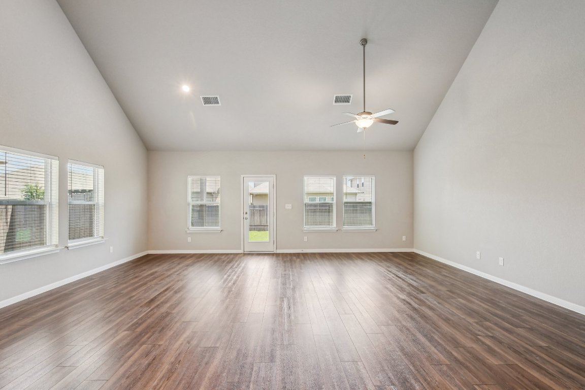 1007 Guadalupe Bass Road Hutto, TX 78634 - Photo 7 of 39 Unfurnished living room featuring high vaulted ceiling, plenty of natural light, dark wood-style flooring, and ceiling fan