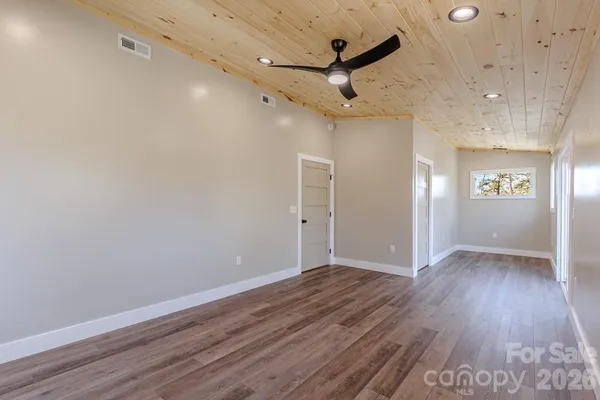 an empty room with wooden floor a ceiling fan and windows