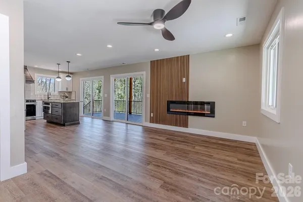 a view of an empty room with wooden floor and a ceiling fan