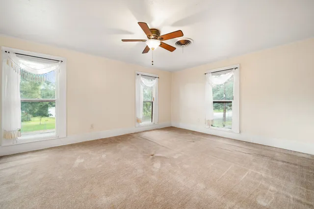 an empty room with a window and a ceiling fan