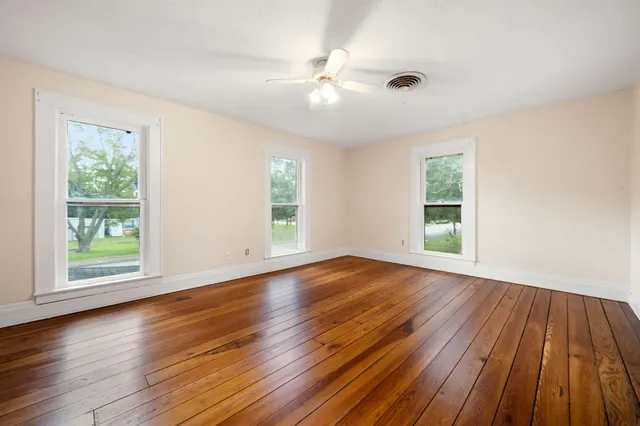 a view of an empty room with wooden floor and a window