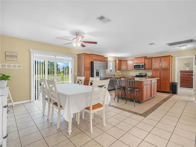 a open kitchen with stainless steel appliances kitchen island granite countertop a stove a sink a dining table and chairs