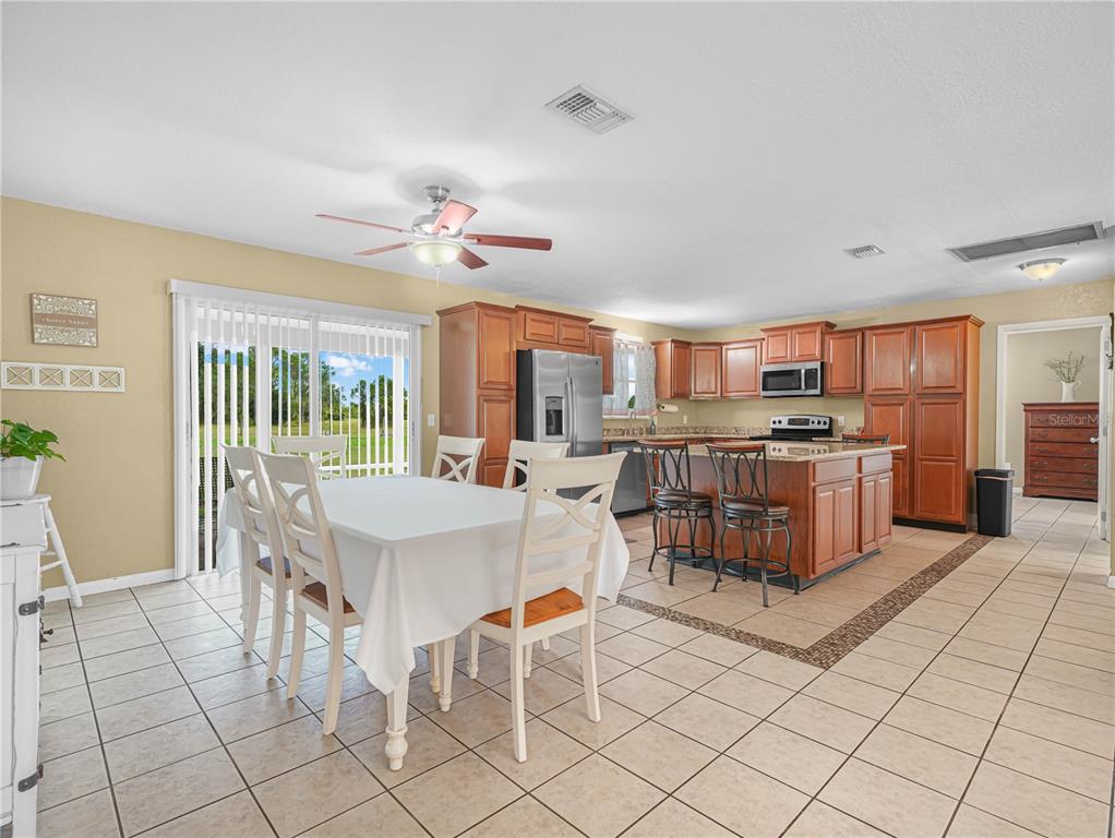 3963 Mammoth Grove Road Lake Wales, FL 33898 - Photo 11 of 42 a open kitchen with stainless steel appliances kitchen island granite countertop a stove a sink a dining table and chairs