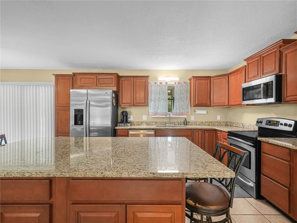 3963 Mammoth Grove Road Lake Wales, FL 33898 - Photo 13 of 42 a kitchen with granite countertop stainless steel appliances a sink a stove top oven a counter space and cabinets