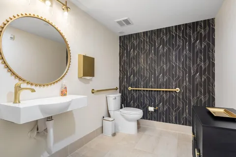 a bathroom with a sink a mirror a toilet and a window