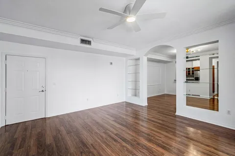 an empty room with wooden floor and ceiling fan