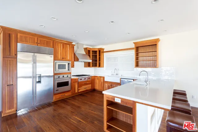a kitchen with stainless steel appliances a refrigerator sink and wooden floor