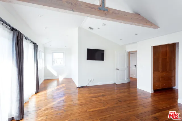 a view of an empty room with wooden floor and windows