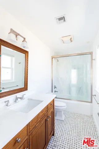 a bathroom with a sink a toilet a mirror and shower