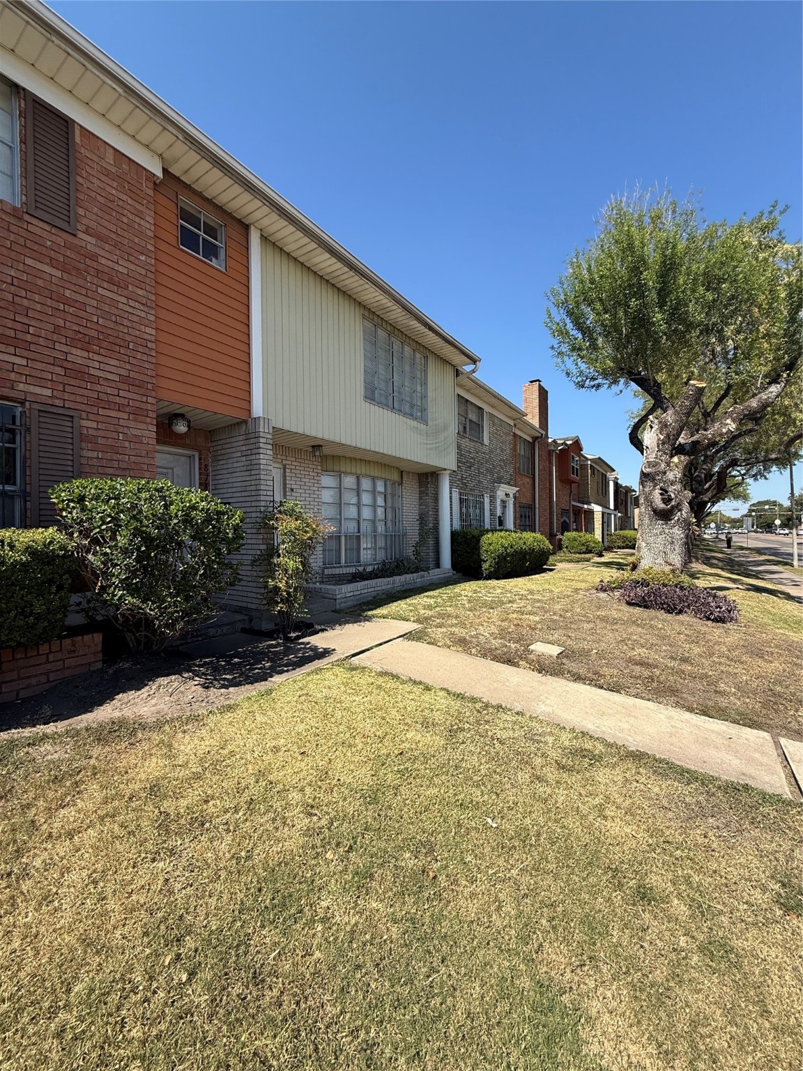 8140 Fondren Road, Unit 8140 Houston, TX 77074 - Photo 26 of 28 brick and siding exterior, featuring a well-maintained front lawn and mature trees. It has large front windows and is located in a row of similar homes, offering a charming suburban feel.
