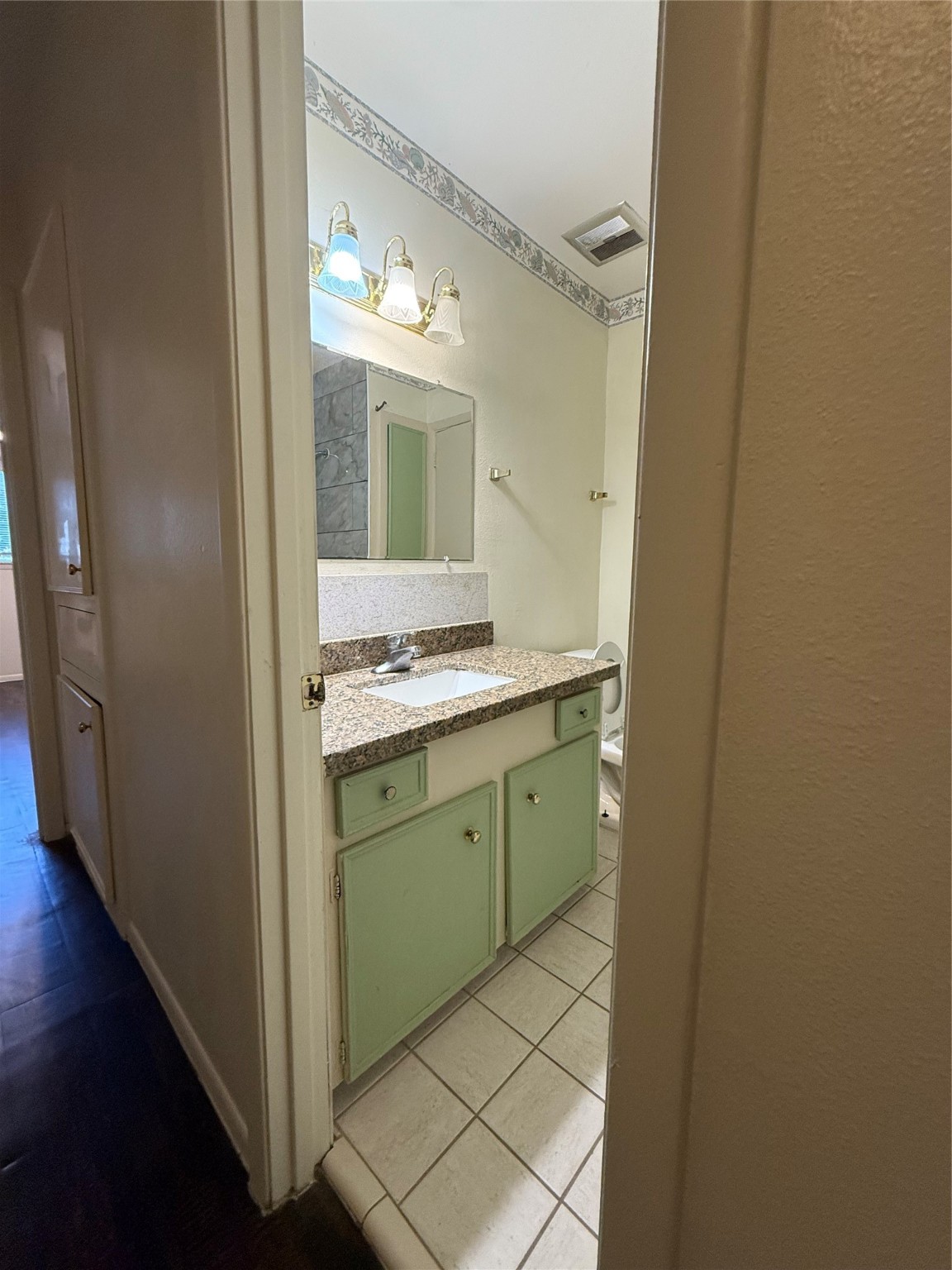 8140 Fondren Road, Unit 8140 Houston, TX 77074 - Photo 8 of 28 A compact bathroom with a granite countertop, mint green cabinets, and a tile floor. The space features a well-lit vanity and a shower area with a tiled wall.