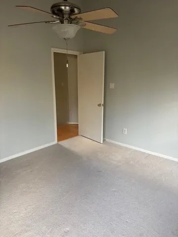 a view of an empty room and chandelier fan