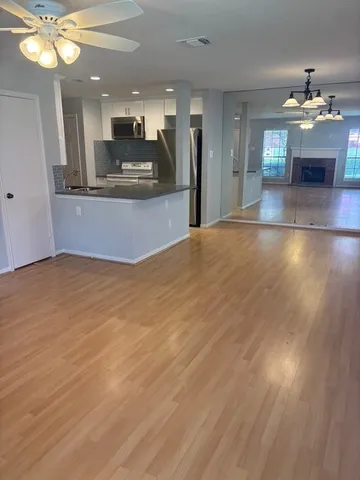 a view of a living room and kitchen with granite countertop wooden floor
