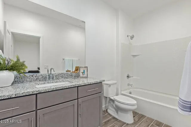 a bathroom with a granite countertop toilet sink and mirror