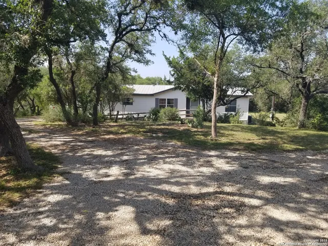 a backyard of a house with large trees and outdoor seating
