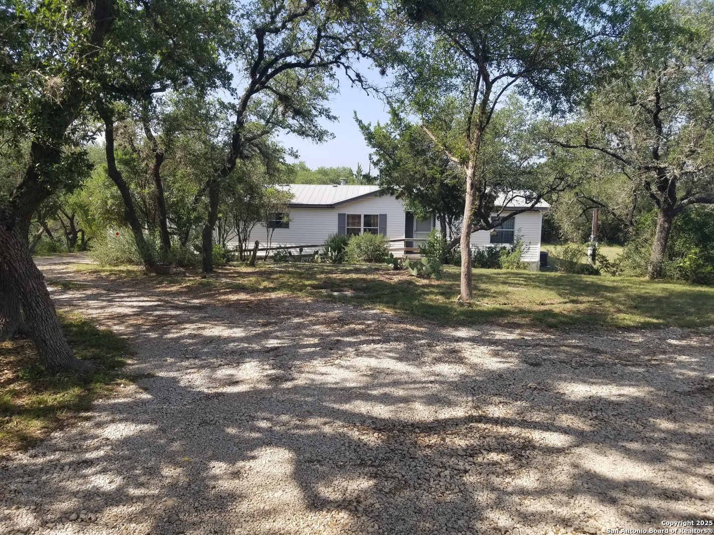 a backyard of a house with large trees and outdoor seating