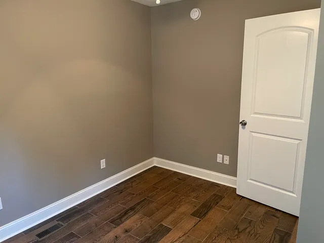 an empty room with wooden floor and cabinet