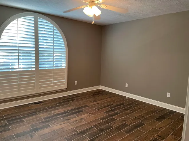a view of an empty room with a window and a chandelier fan