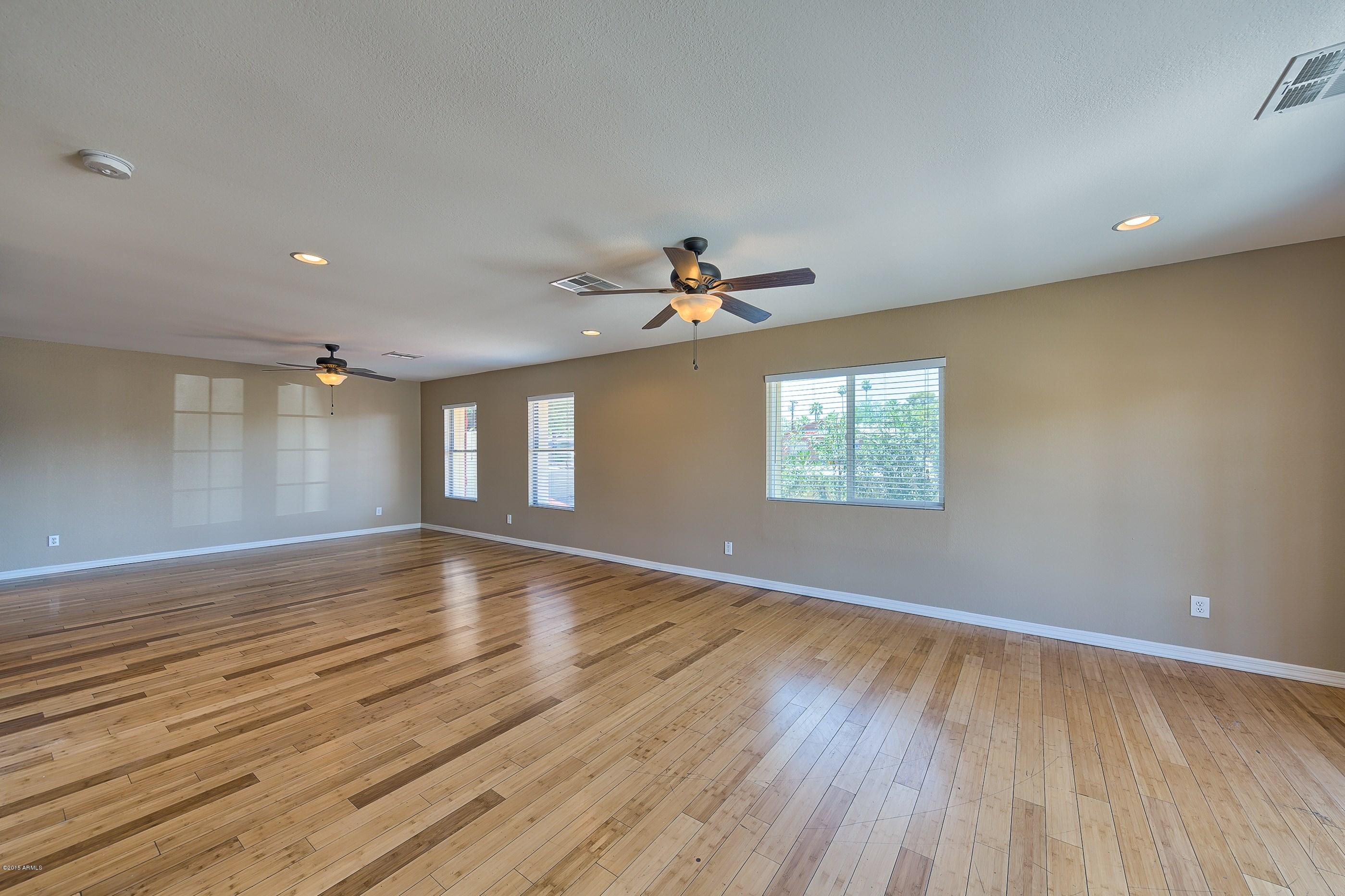 1601 North 13th Avenue Phoenix, AZ 85007 - Photo 4 of 18 an empty room with wooden floor chandelier fan and windows