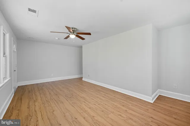 a view of room with hardwood floor and a ceiling fan